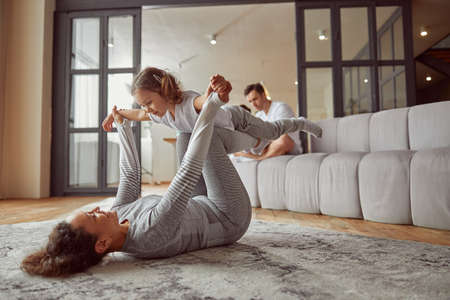 Happy woman playing with daughter at homeの写真素材