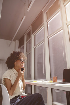 Happy lady talking on her mobile phone at work desk