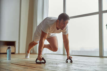 Strong guy during core training indoors near window