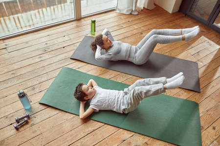 Active woman doing workout with son indoorsの写真素材