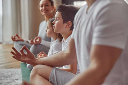Calm little boy enjoying meditation with family indoorsの写真素材