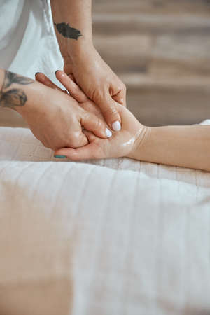 Professional confident massage master is doing procedures to caucasian woman in minimalistic modern cabinetの写真素材