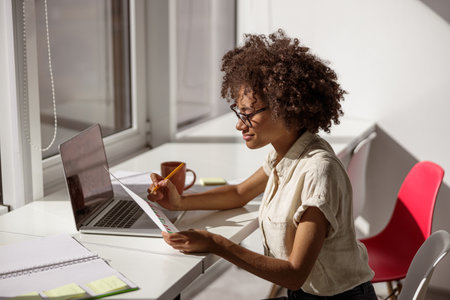 Young Afro American lady looking at the report in the office