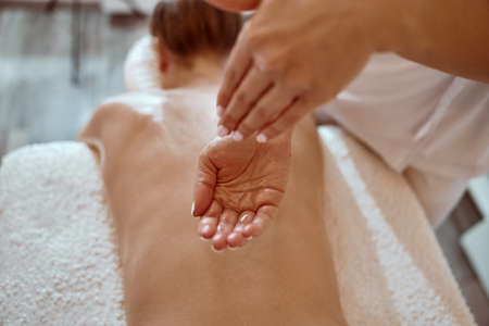 Professional confident massage master is doing procedures to caucasian woman in minimalistic modern cabinetの写真素材