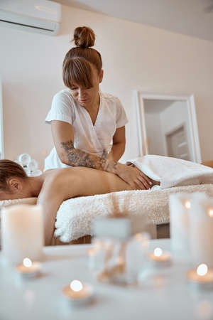 Professional confident massage master is doing procedures to caucasian woman in minimalistic modern cabinetの写真素材