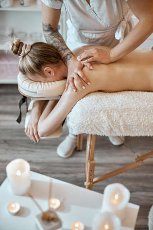 Professional confident massage master is doing procedures to caucasian woman in minimalistic modern cabinetの写真素材