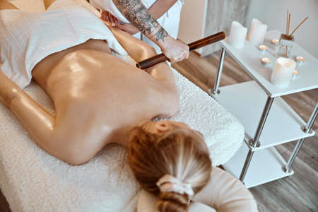 Professional confident massage master is doing procedures to caucasian woman in minimalistic modern cabinetの写真素材