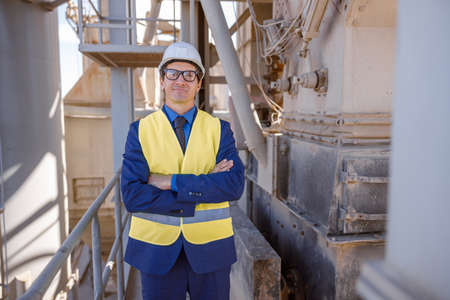 Male engineer standing on metal bridge at factory