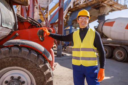 Joyful male worker standing by vehicle at factoryの写真素材