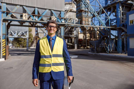 Cheerful male engineer standing outdoors at factoryの写真素材