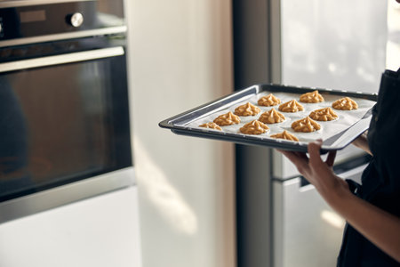 Professional confident woman is preparing custard cakes at light modern kitchen at homeの写真素材