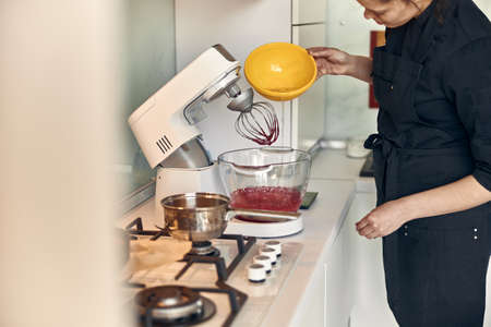 young beautiful mixed race woman is preparing marshmallow at light modern kitchen homeの写真素材