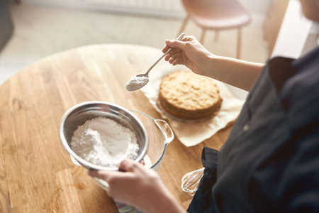 young professional female cook is preparing tasty cake at her light modern kitchenの写真素材
