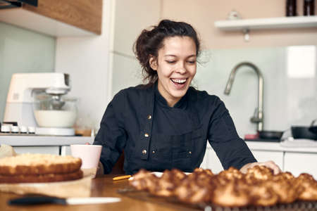 young professional female cook is preparing tasty cake at her light modern kitchenの写真素材