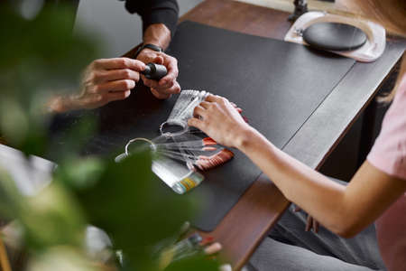 Male confident manicure master in salon with beautiful female light hair woman clientの写真素材