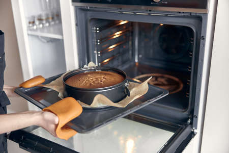young professional female cook is preparing tasty cake at her light modern kitchenの写真素材