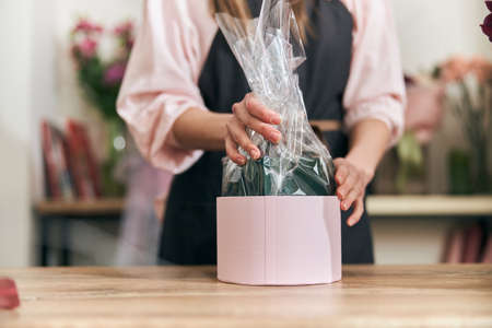Professional florist young woman is doing bouquets at flower shopの写真素材