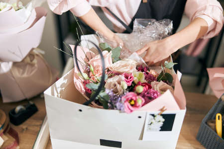 Professional florist young woman is doing bouquets at flower shopの写真素材