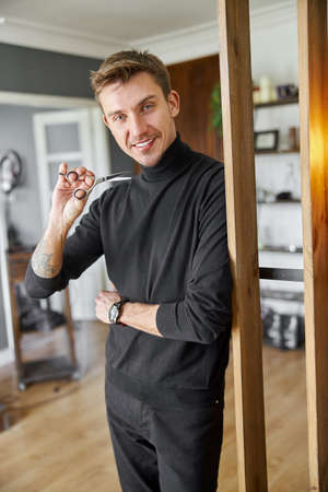 Male happy smiling hairdresser at his modern salonの写真素材
