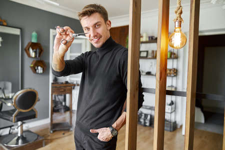 Male happy smiling hairdresser at his modern salonの写真素材