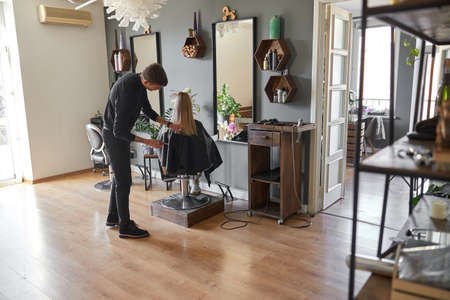 Hairdresser is choping hair of blonde woman is salonの写真素材