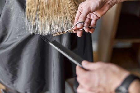 Hairdresser is choping hair of blonde woman is salonの写真素材