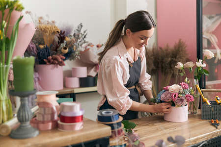 Professional florist young woman is doing bouquets at flower shopの写真素材