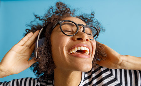 Cheerful young woman in headphones enjoying musicの写真素材