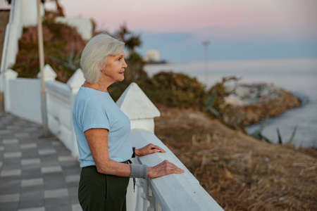 Attractive elderly woman standing at beautiful parkの写真素材