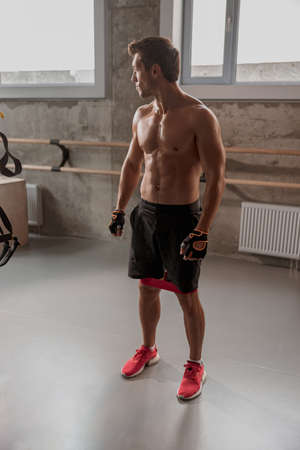 Athletic young man standing in the gym in sport shorts