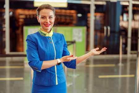 Cheerful female flight attendant pointing at something at airport