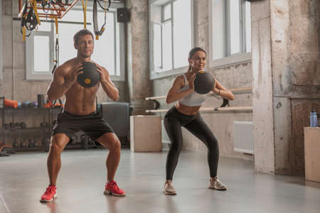Beautiful female working out with personal trainer indoors