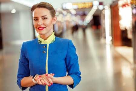 Cheerful woman airline worker standing in airport terminalの写真素材