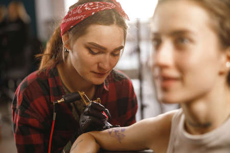 Focused female tattoo master making tattoo in salonの写真素材