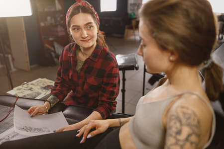 Woman tattoo master looking at the clientの写真素材
