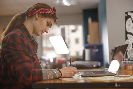 Portrait of concentrated woman drawing something while sitting in her officeの写真素材