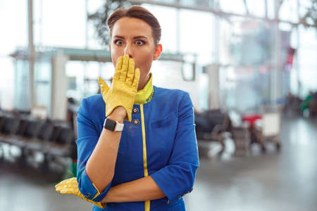 Shocked flight attendant covering mouth with hand at airportの写真素材