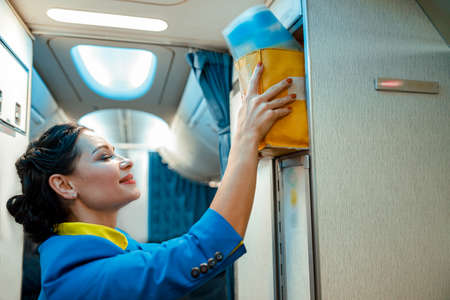 Stewardess putting bag in overhead shelf in aircraft cabinの写真素材