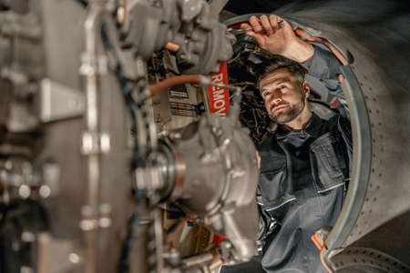 Bearded man mechanic repairing airplane in hangarの写真素材