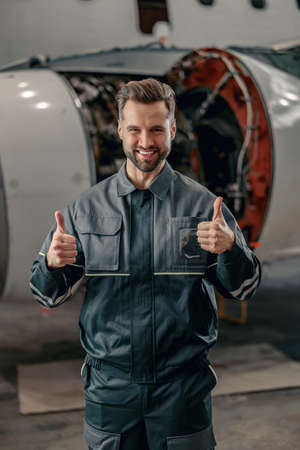 Cheerful airline mechanic showing approval gesture in hangar