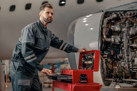 Bearded man airline mechanic working in aircraft hangar