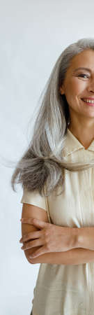 Portrait of Asian female model with long grey hair and crossed arms on light backgroundの写真素材
