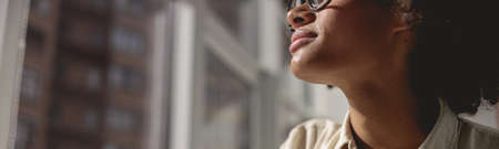 Pretty Afro American woman looking out the windowの写真素材