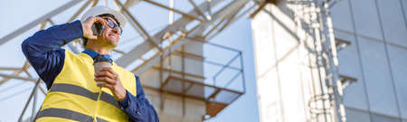 Cheerful male worker talking on cellphone outdoors at factory