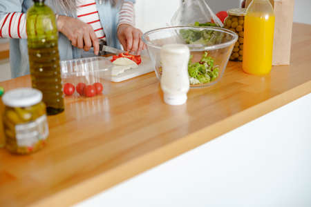 Female hands cutting fresh pepper with knife in kitchenの写真素材