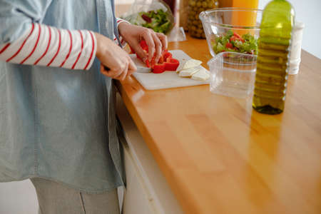 Female hands cutting bell pepper for salad in kitchenの写真素材