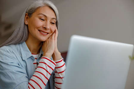 Joyful woman watching video on laptop at home