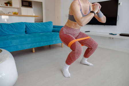 Sporty woman doing exercise with resistance band at home