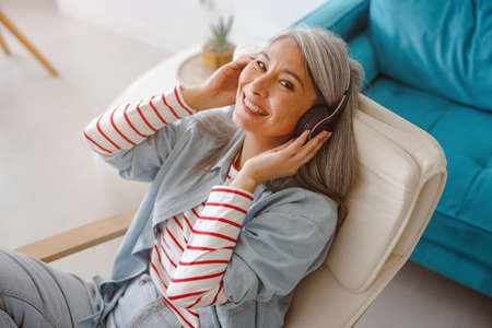 Cheerful woman listening to music at homeの写真素材