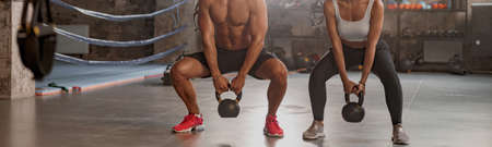 Male personal trainer training female client in gym